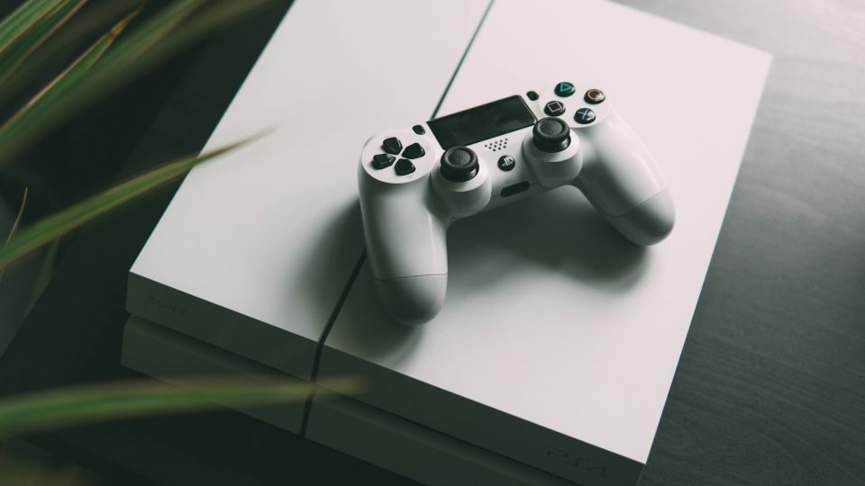 selective focus photography of white Sony PS4 console with wireless controller